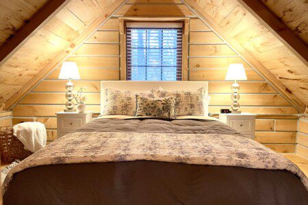 🛏️ Retreat to Upstairs Bedroom #2—queen bed, soft linens, fluffy pillows, and a USB outlet on the nightstand for charging. The perfect log cabin haven for a restful night’s sleep! 🌙🔌