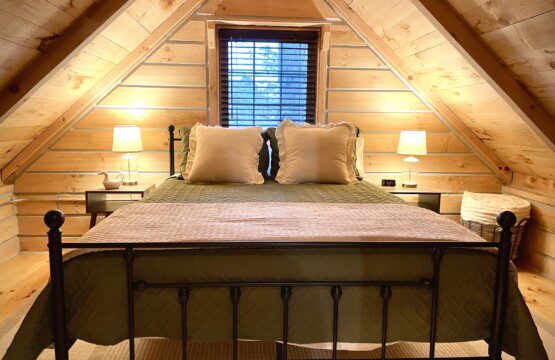 🛏️ Retreat to Upstairs Bedroom #1—queen bed, soft linens, fluffy pillows, and a USB outlet on the nightstand for charging. The perfect log cabin haven for a restful night’s sleep! 🌙🔌