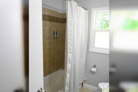 Hallway bathroom with tub and shower.