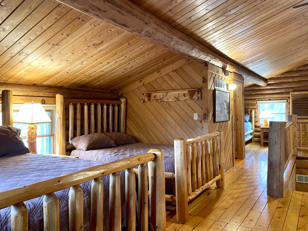 Bedroom #2: upstairs - two beds in room (one queen and one full) & easy charging stations beside beds; open loft design - an airy, connected space overlooking the rest of the cabin, though not a private room.