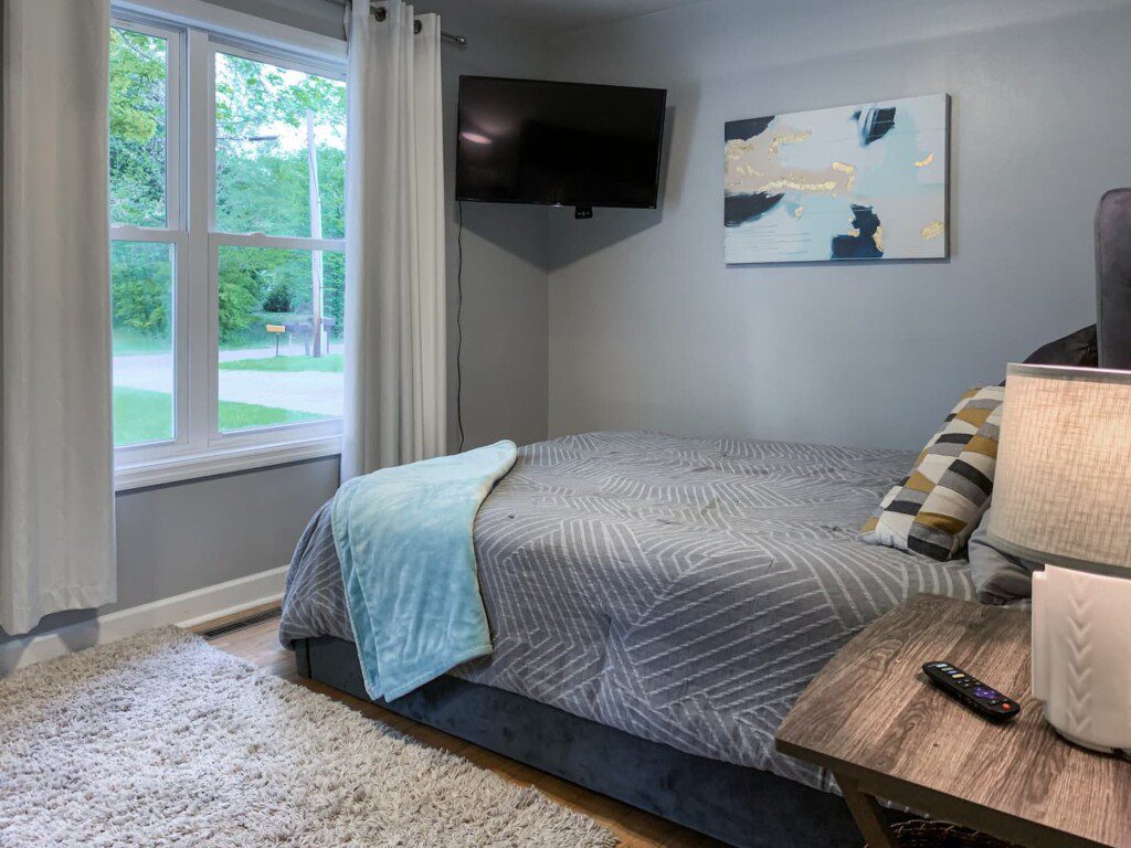 Bedroom #2 with queen bed; nightstand a clock w/ USB and outlets to make charging devices super convenient with 32-inch Roku Smart TV with YouTube TV access.