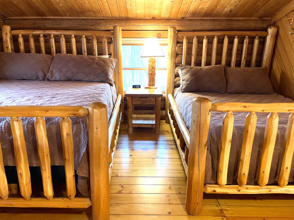 Bedroom #2: upstairs - two beds in room (one queen and one full) & easy charging stations beside beds; open loft design - an airy, connected space overlooking the rest of the cabin, though not a private room.