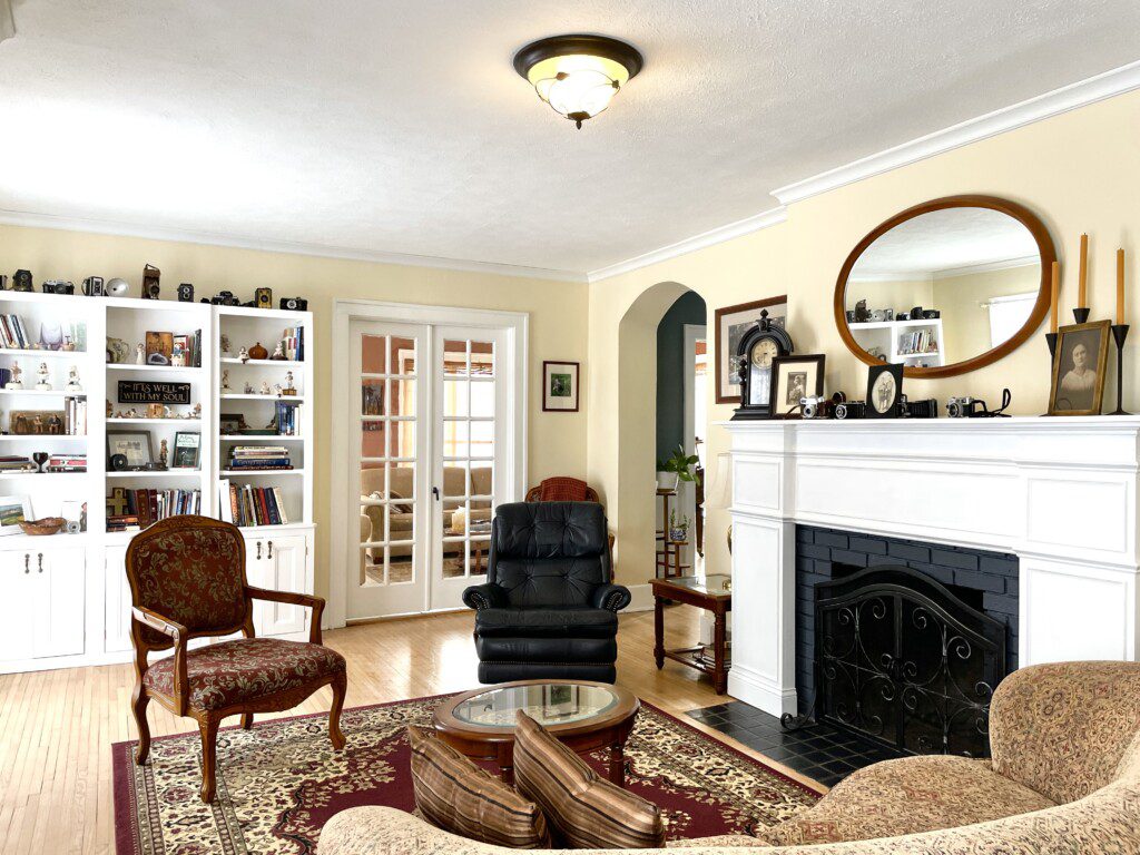 Curl up with a good book beside the fireplace in this charming sitting room 📚🔥 — built-in shelves, a classic arched doorway, and a plush chair create your perfect reading escape.
