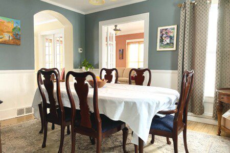 Elevate your mealtime into an occasion 🍽️🌿 — gather around this elegantly set dining room with a crisp tablecloth, classic wood chairs, and lush greenery for a meal that feels truly special.